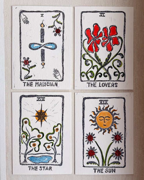 Four illustrated tarot-style cards arranged in a 2x2 grid on a light beige wall. The cards are labeled The Magician, The Lovers, The Star, and The Sun, with black outlines and colorful drawings in red, blue, green, and yellow.